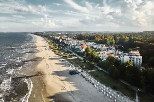 Bansin Strand mit Gebäuden und Bäumen im Vordergrund, Himmel mit Wolken im Hintergrund.