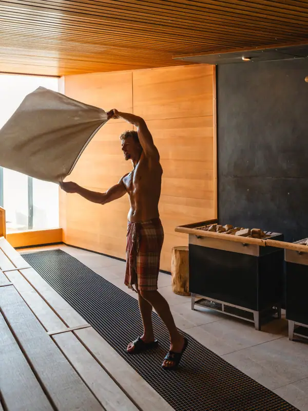 Sauna Ein Mann hält ein Handtuch in einem Raum.