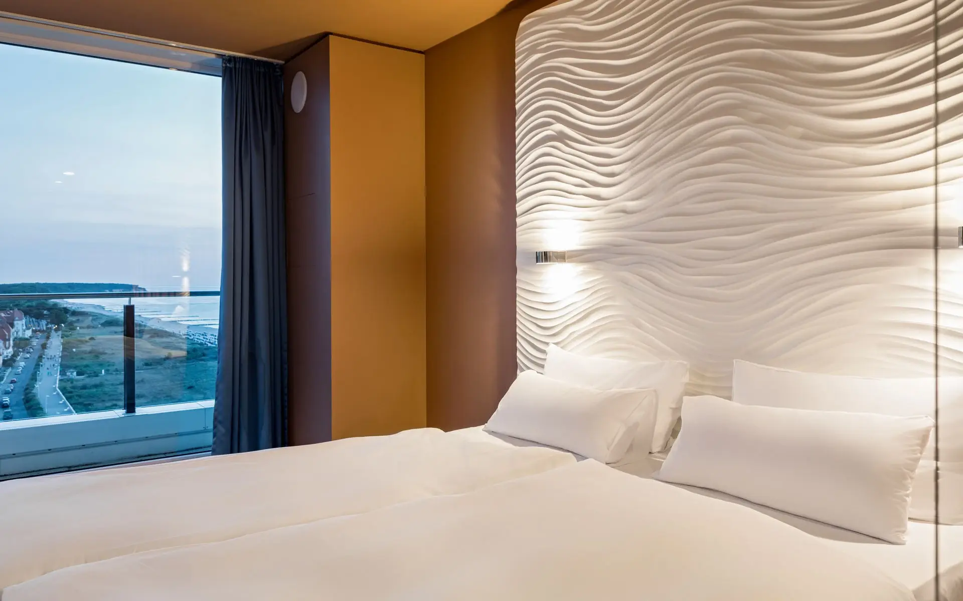 Ein Kingsizebett und ein großes Fenster mit Blick auf das Meer