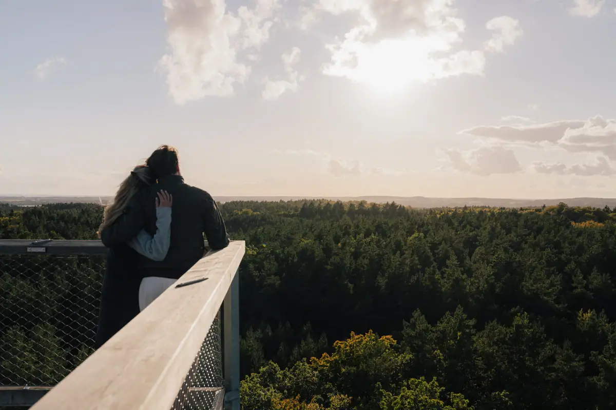 Ausblick Baumwipfelpfad Usedom Ein Mann und eine Frau umarmen sich auf einem Balkon mit Blick auf dem Baumwipfelpfad