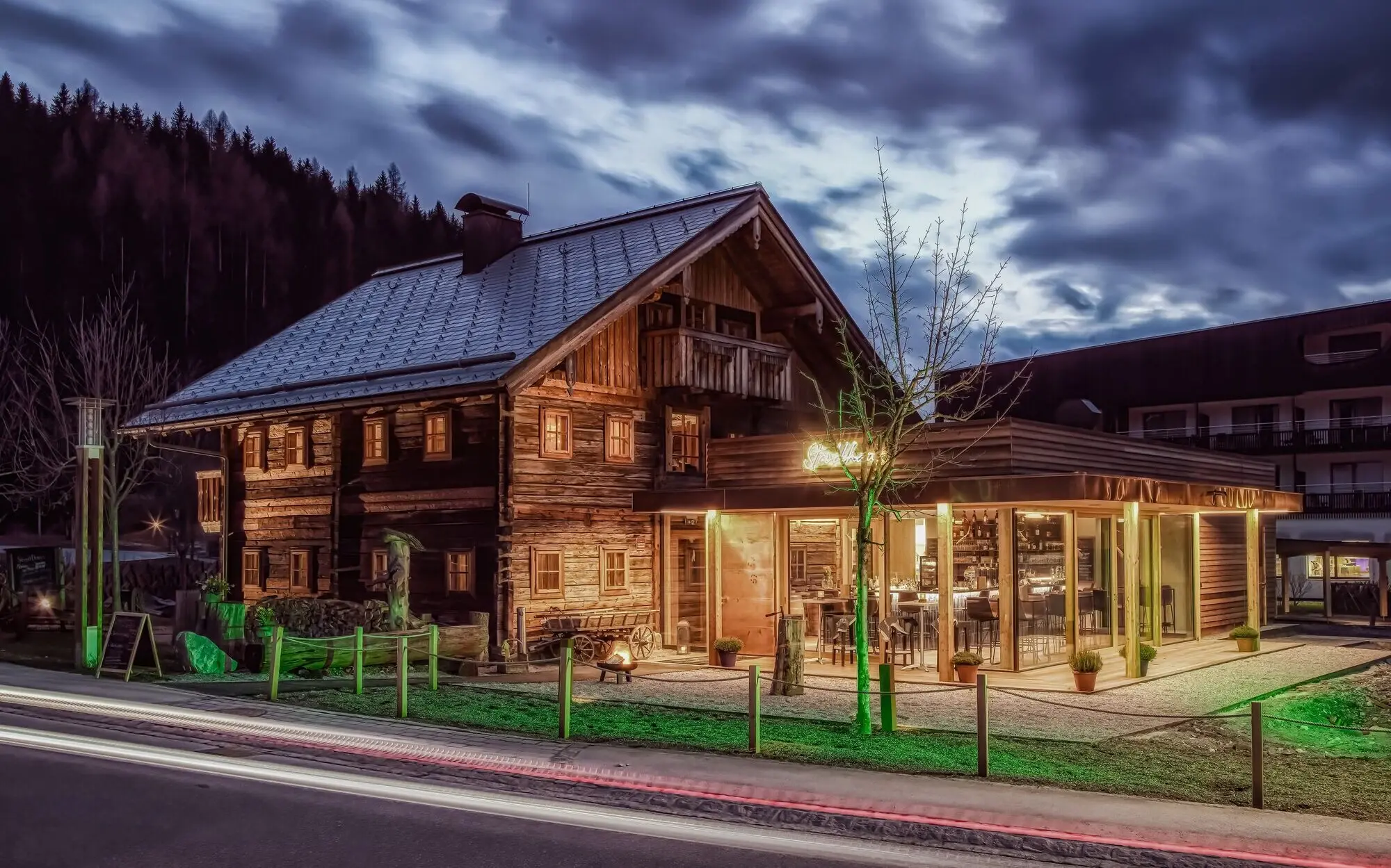 Stroblhaus Werfenweng Ein altes Holzhaus mit einem Wintergarten und einem Baum davor.