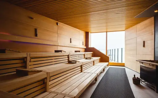 Eine Holzsauna mit einem großen Fenster, durch das Tageslicht hinein fällt. Eine Holzsauna mit einem großen Fenster, durch das Tageslicht hinein fällt.
