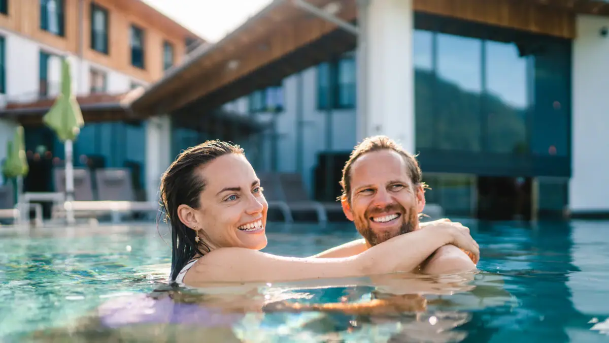 Außenpool im aja Ruhpolding Ein Mann und eine Frau lächelnd in einem Schwimmbecken.
