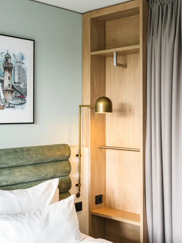Neues Doppelzimmer im aja Warnemünde Bett mit Lampe und Regal in einem Zimmer