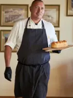 Mann in Schürze hält ein Brotlaib.