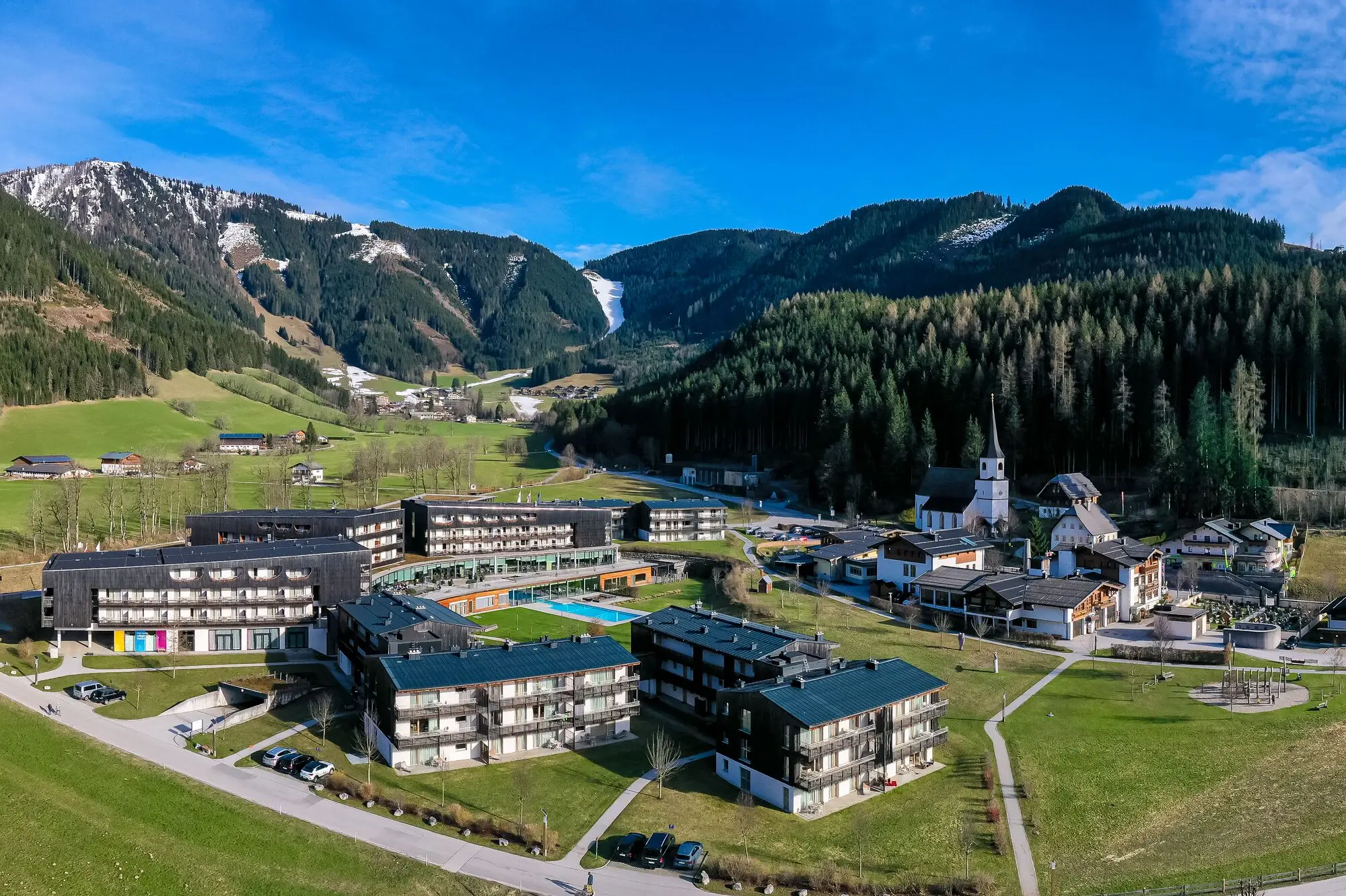 Bergresort Werfenweng Eine Gruppe von Gebäuden in einem Dorf mit Bäumen und Himmel im Hintergrund.