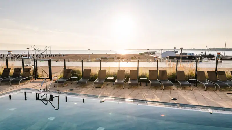 Wellness mit Aussicht in Travemünde Ein Pool mit Stühlen und einem Strand im Hintergrund.