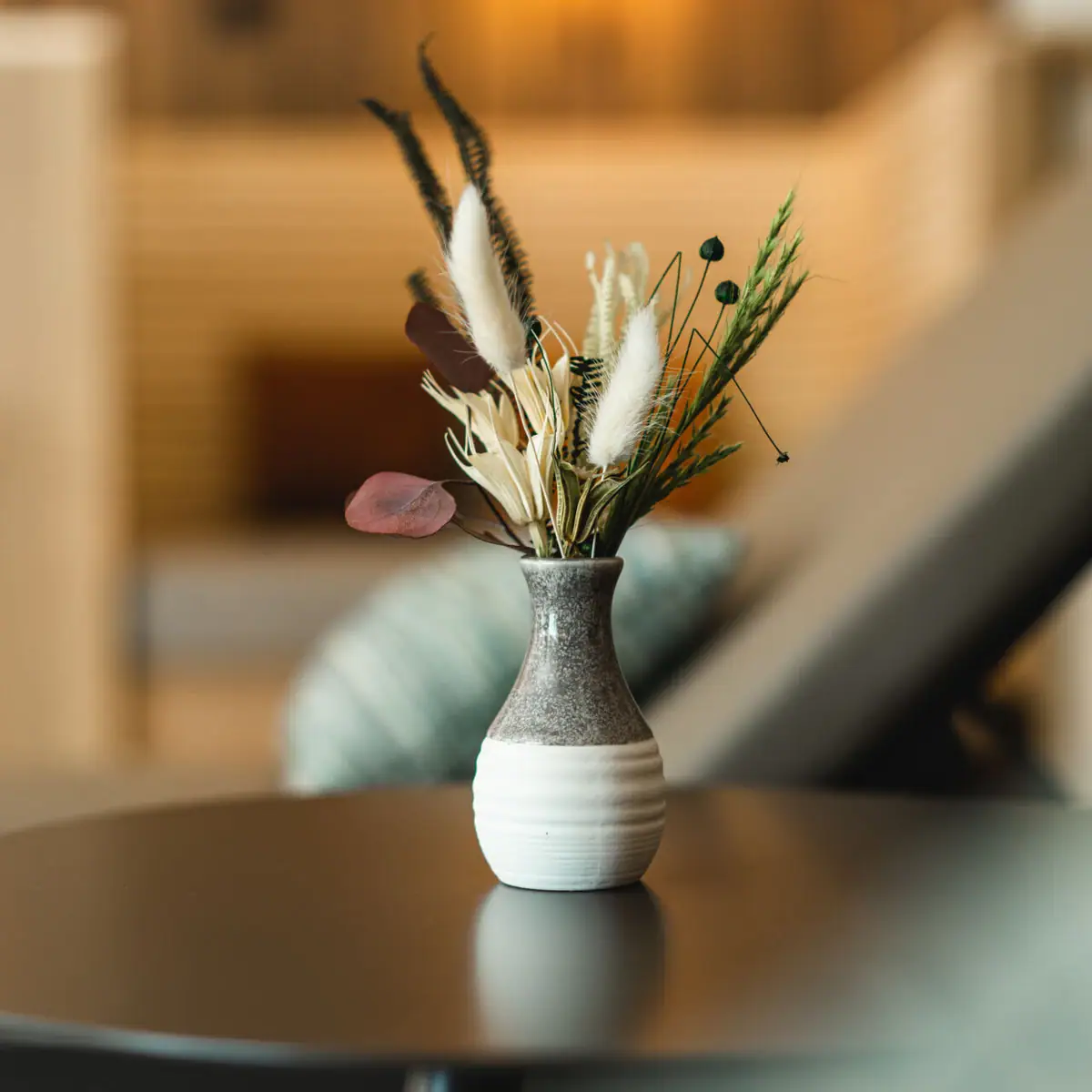 Vase Eine Vase mit getrockneten Blumen auf einem Tisch.