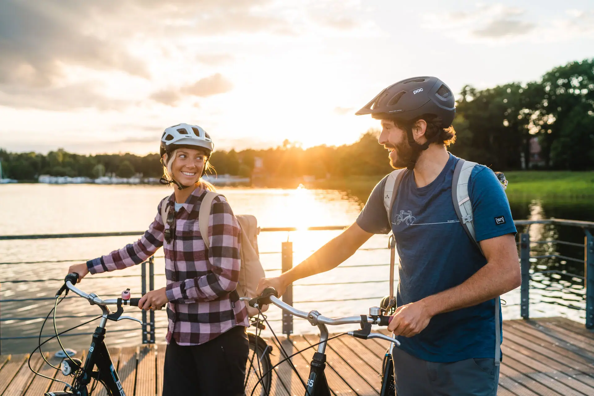 Fahrradtour in Bad Saarow Ein Mann und eine Frau mit Helmen und Fahrrädern auf einem Steg.