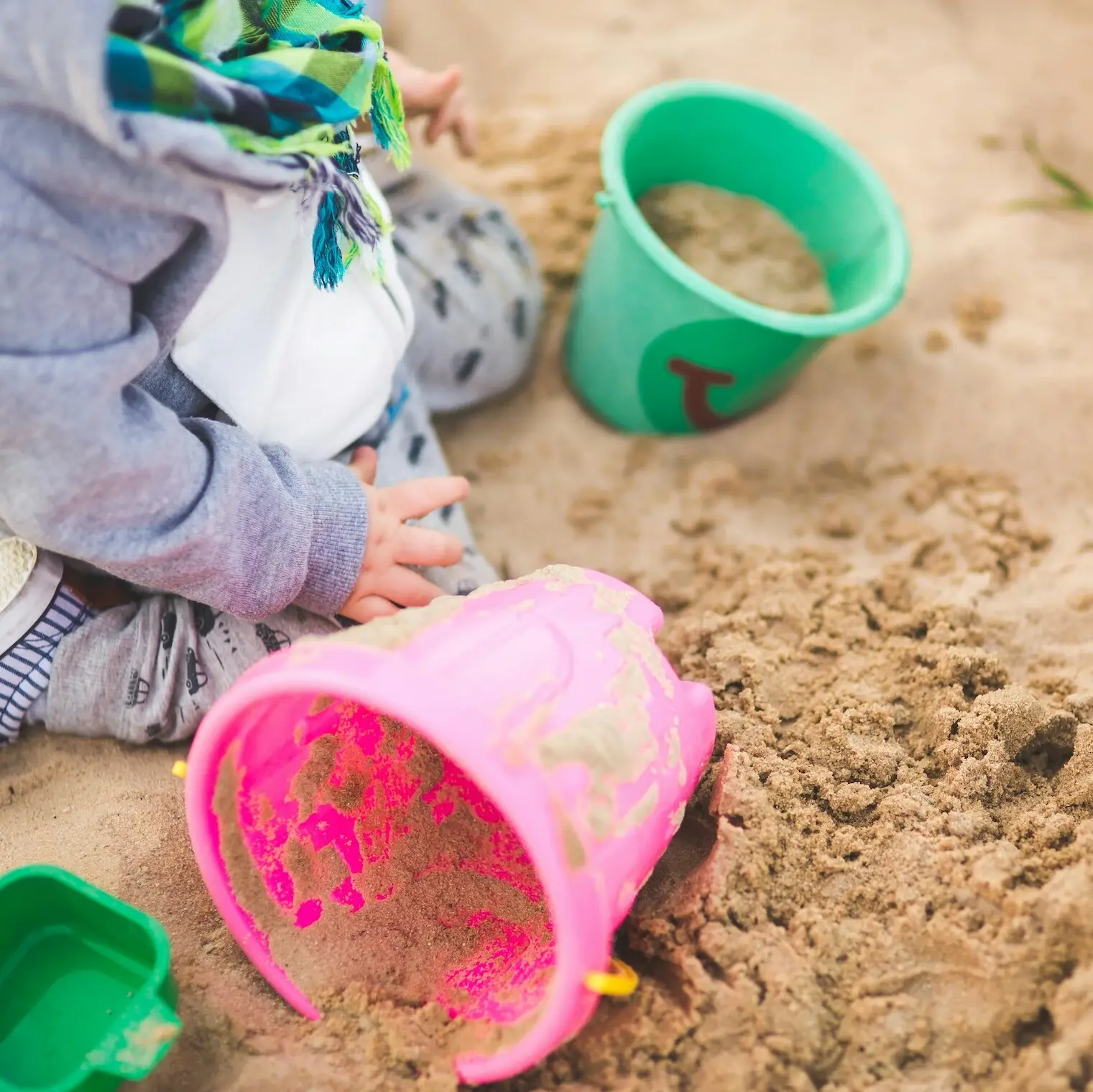 Sankasten Ein Kind spielt mit einem Eimer im Sand.