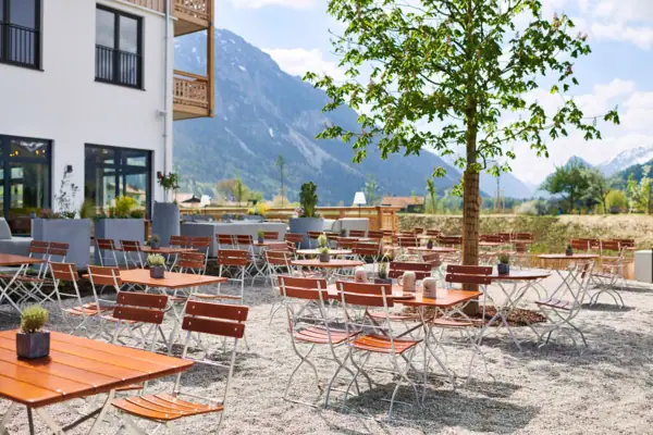 Biergarten aja Ruhpolding Eine Gruppe von Tischen und Stühlen im Freien vor dem aja Ruhpolding.