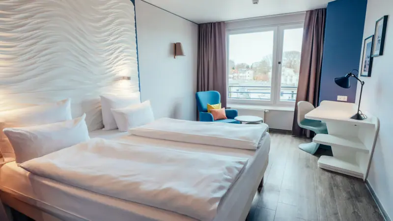 Doppelzimmer Ein Zimmer mit zwei Betten und einem Tisch.