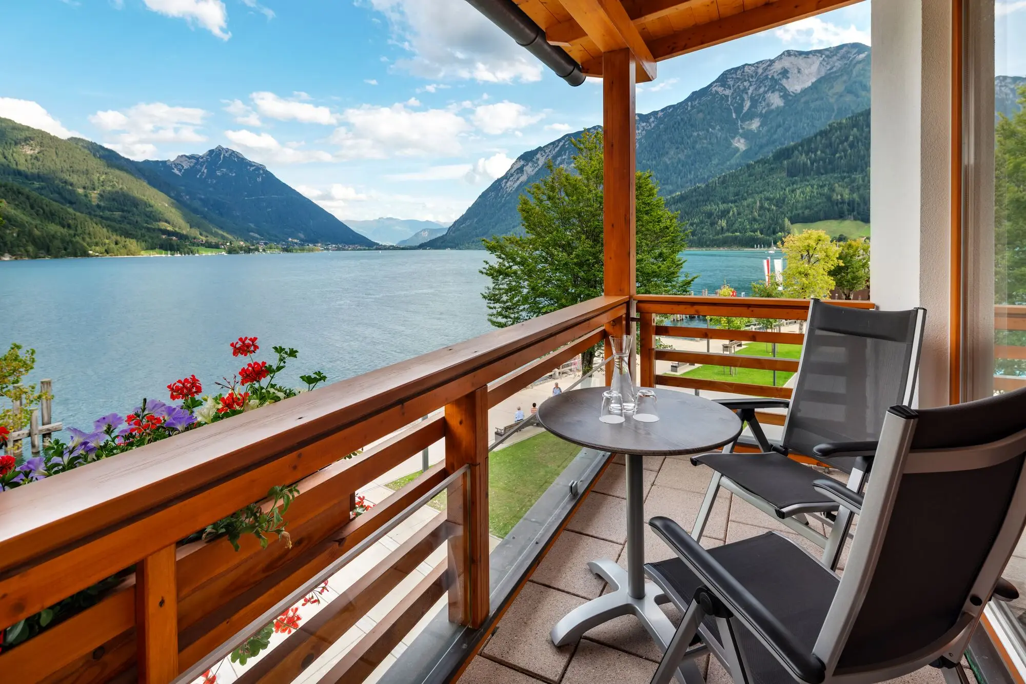 Balkon mit Seeblick Balkon mit Tisch und Stühlen, der auf einen See blickt.
