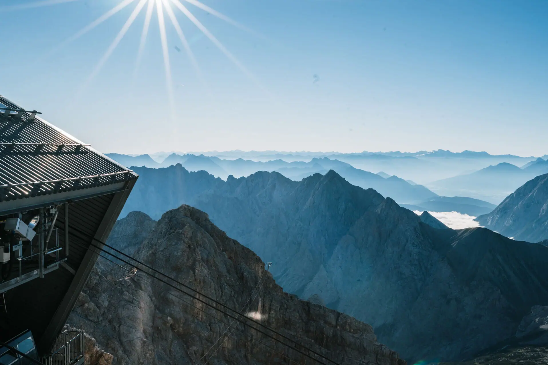 Zugspitze Aussicht Ein Bergmassiv mit einer Seilbahn und strahlendem Sonnenschein.