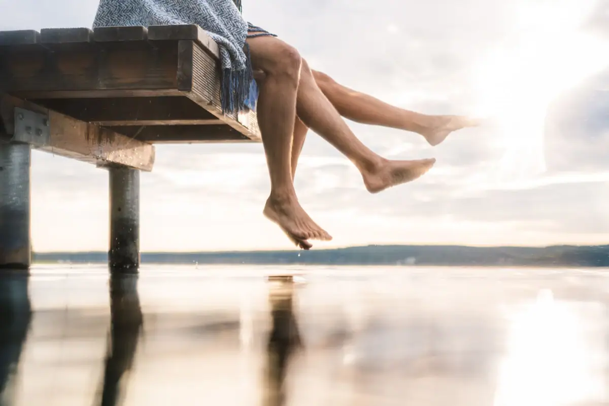 Steg Bad Saarow Zwei Personen sitzen auf einem Steg am Wasser.