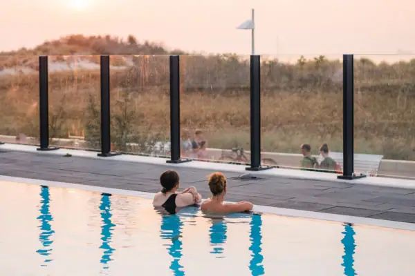 Außenpool im aja Warnemünde Zwei Personen schwimmen in einem Pool.