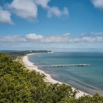 Göhren Ein Strand mit einem Pier und Bäumen.