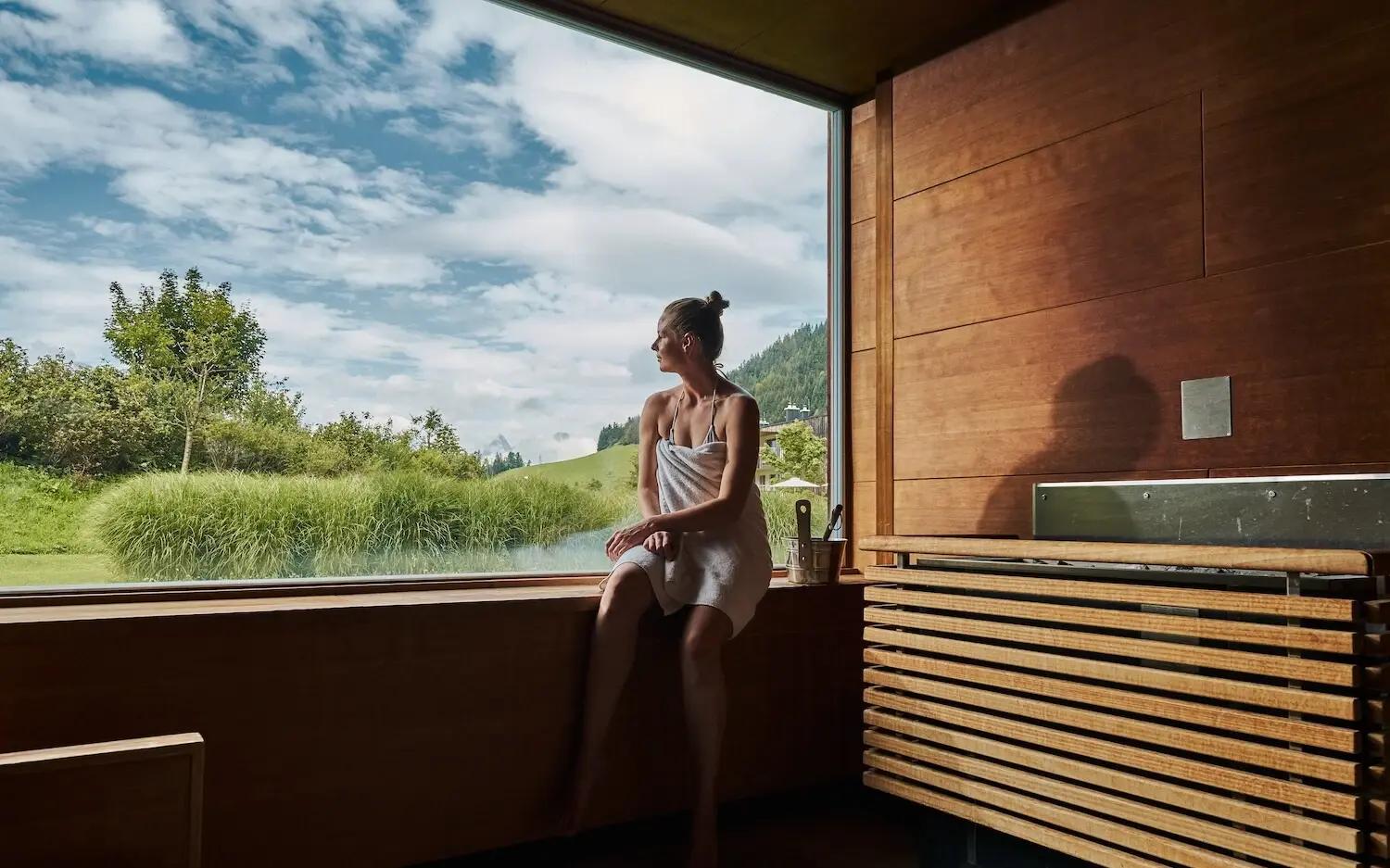 Sauna aja Werfenweng Frau sitzt in einer Sauna auf einer Fensterbank und blickt nach draußen.