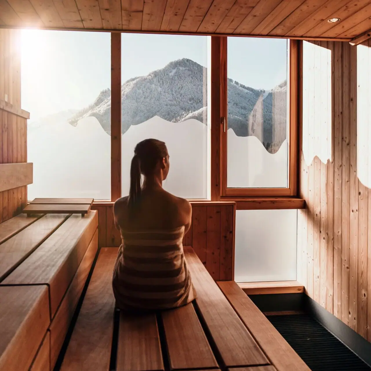 Sauna im aja Ruhpolding Eine Frau sitzt in einer Sauna.