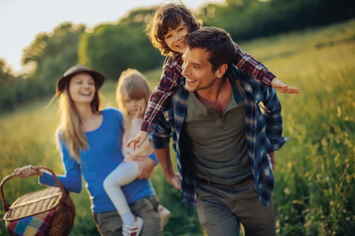 Familienausflug Ein Mann trägt ein Kind auf seinen Schultern im Freien.