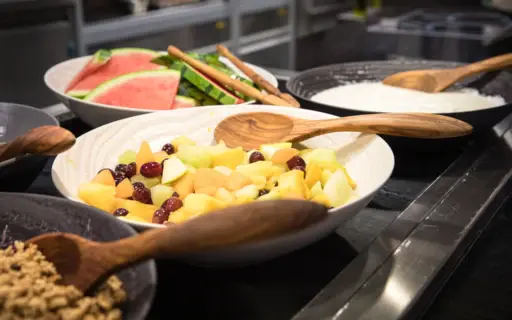 Ein Buffet mit Müsli und Früchten in großen weißen Schalen mit Holzlöffeln. Ein Buffet mit Müsli und Früchten in großen weißen Schalen mit Holzlöffeln.