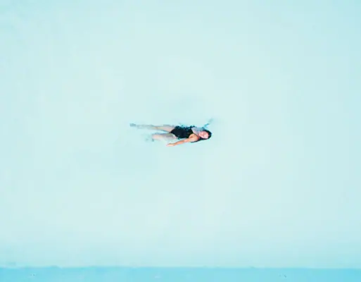 Schwimmen im Pool Eine Frau schwimmt im Pool auf dem Rücken.