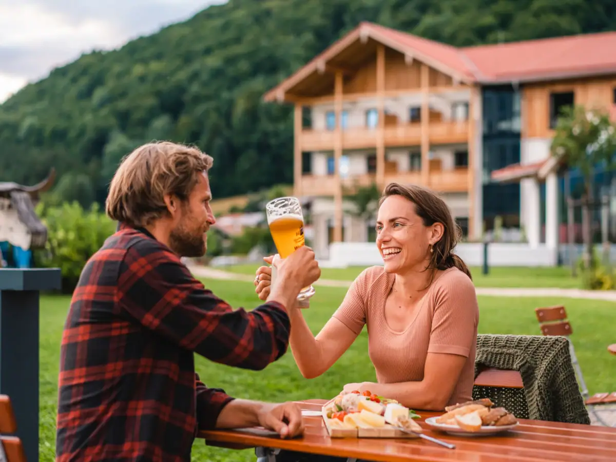 Biergarten im aja Ruhpolding Ein Mann und eine Frau sitzen an einem Tisch mit Essen und Getränken.