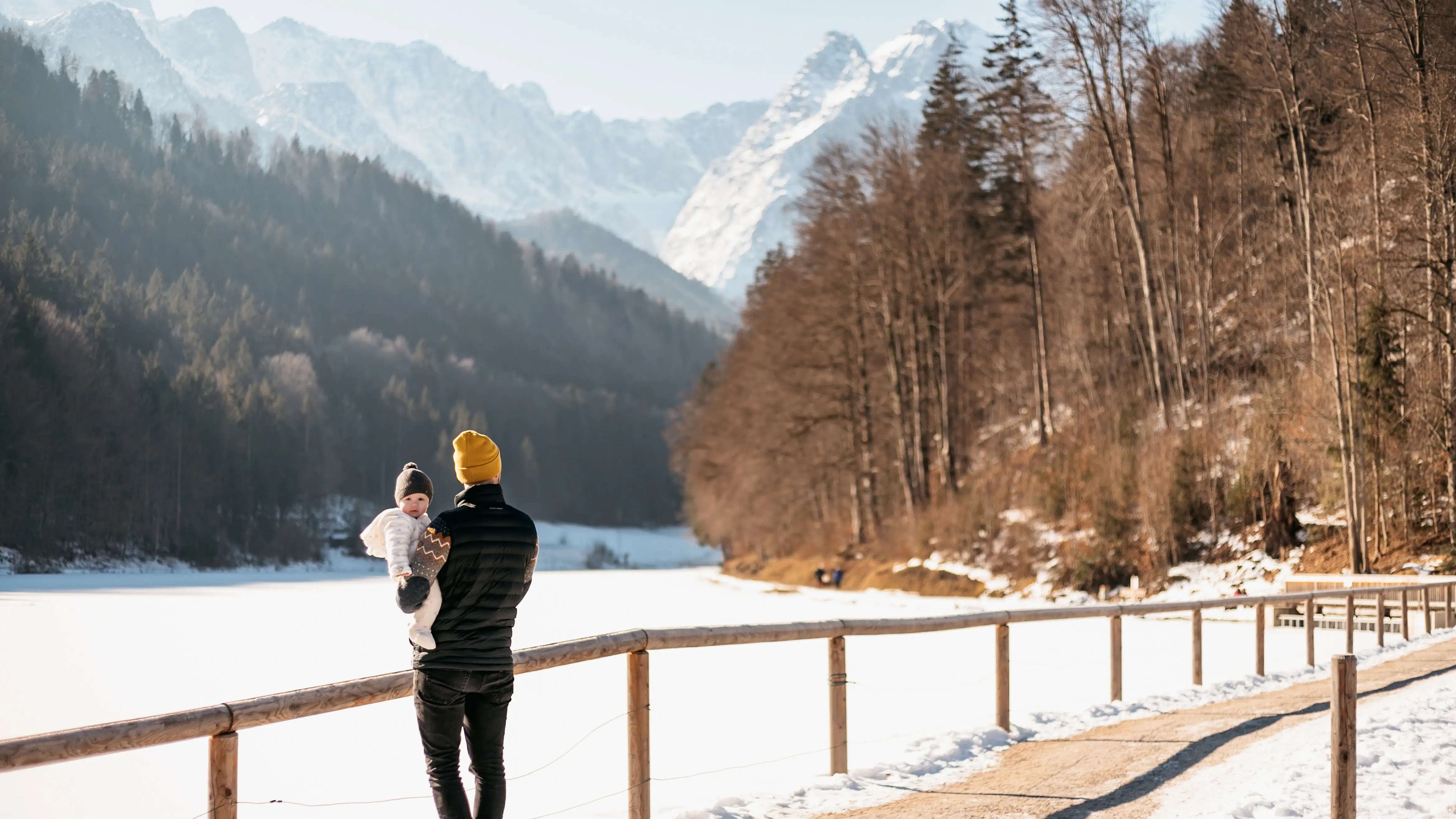 Riessersee in Winter Ein Mann hält ein Baby auf einer verschneiten Straße.