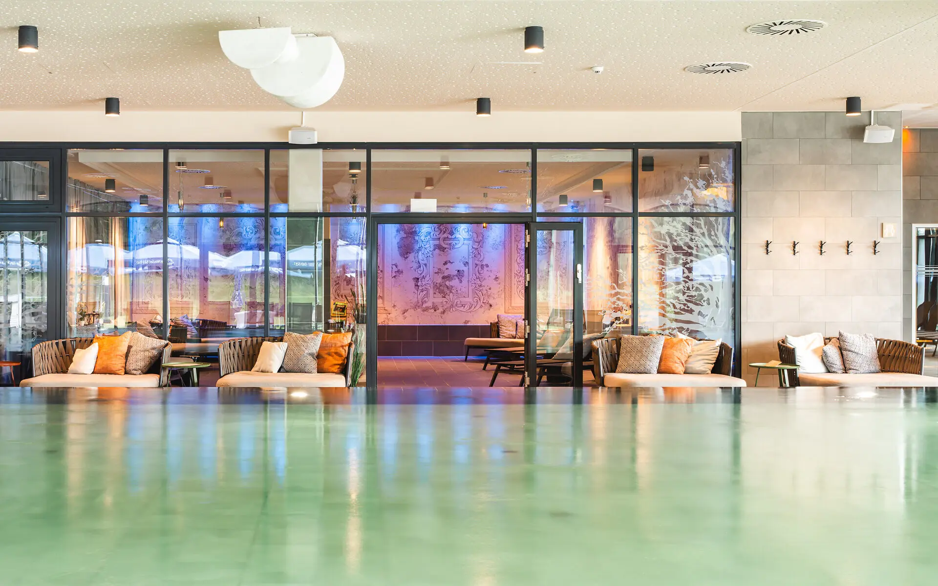 Innenpool aja Bad Saarow Der Innenpool des aja Bad Saarow mit gemütlichen Liegen im Hintergrund und dem dahinter liegenden Ruhebereich in warmen Farben.