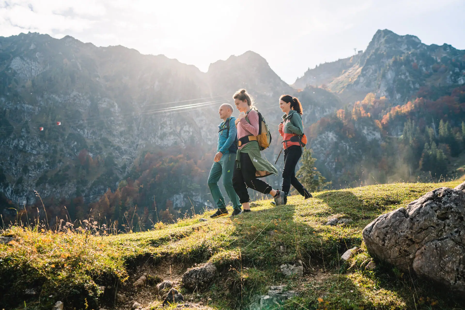 Eine Gruppe von Menschen wandert auf einem Hügel mit Bergen im Hintergrund.