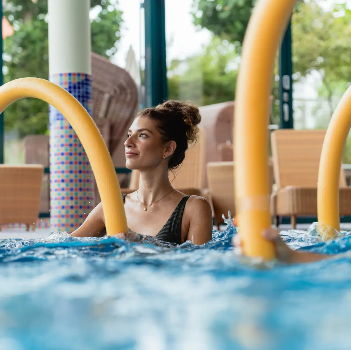 Aqua Fitness Eine Frau im Pool mit gelben Schwimmnudeln beim Aqua-Fitness.