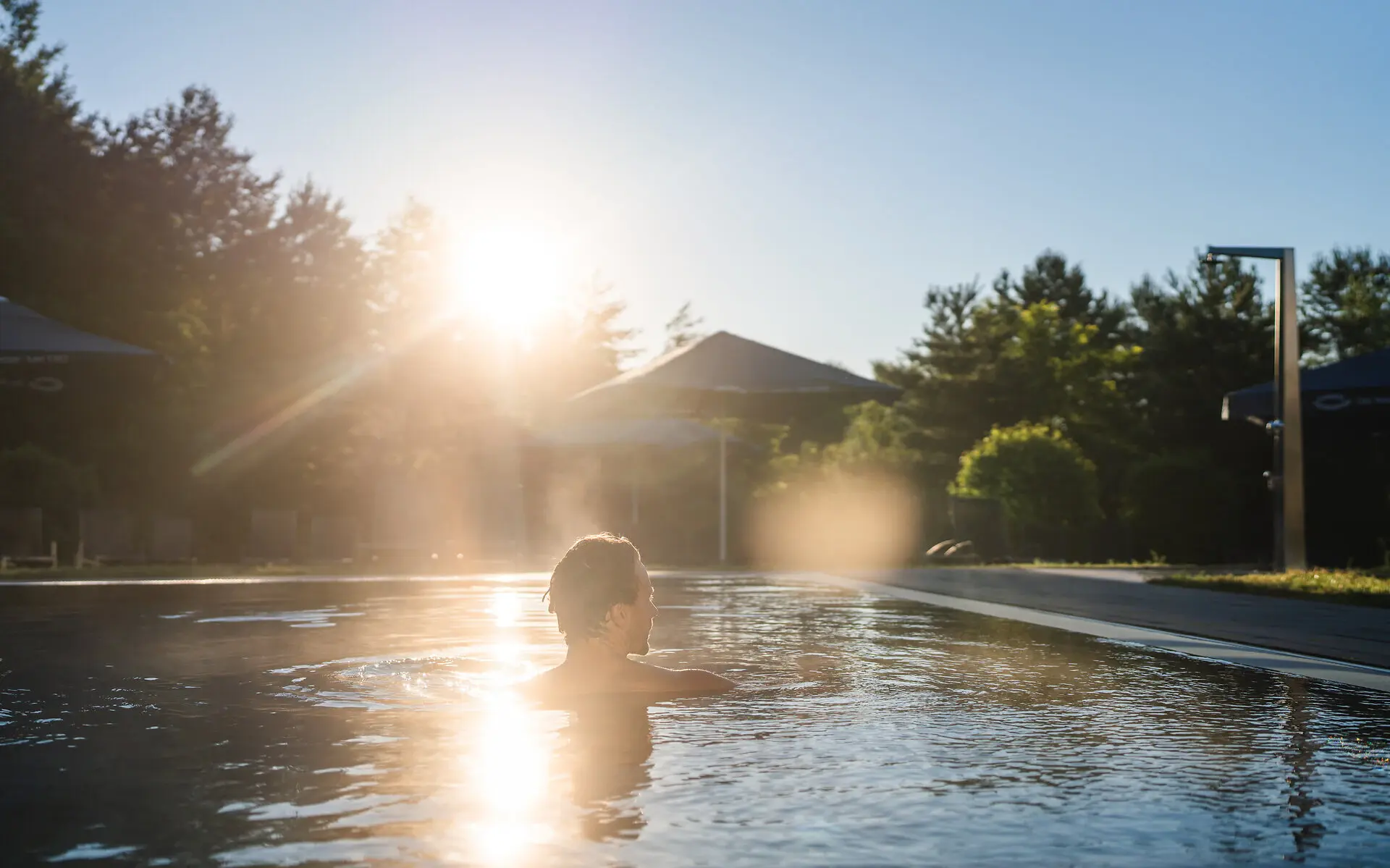 Außenpool aja Bad Saarow Ein Mann schwimmt bei Sonnenaufgang im Außenpool des aja bad Saarow.