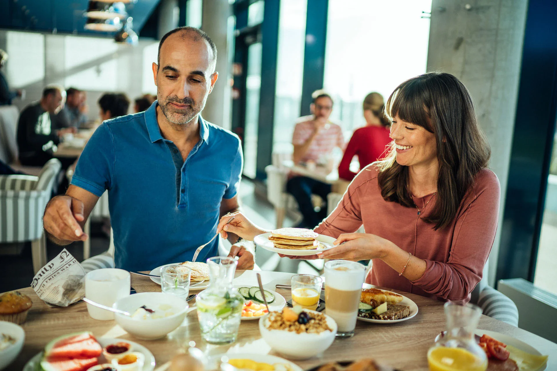 Ein Paar genießt ein reichhaltiges Frühstück in einem modernen Restaurant mit fröhlicher Atmosphäre.