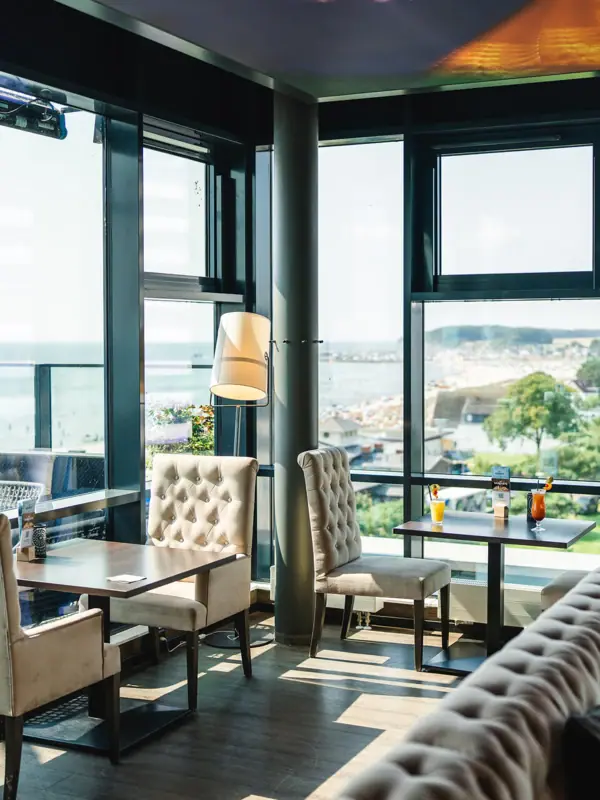 Bar Ein Raum mit einem großen Fenster, Tischen und Stühlen.