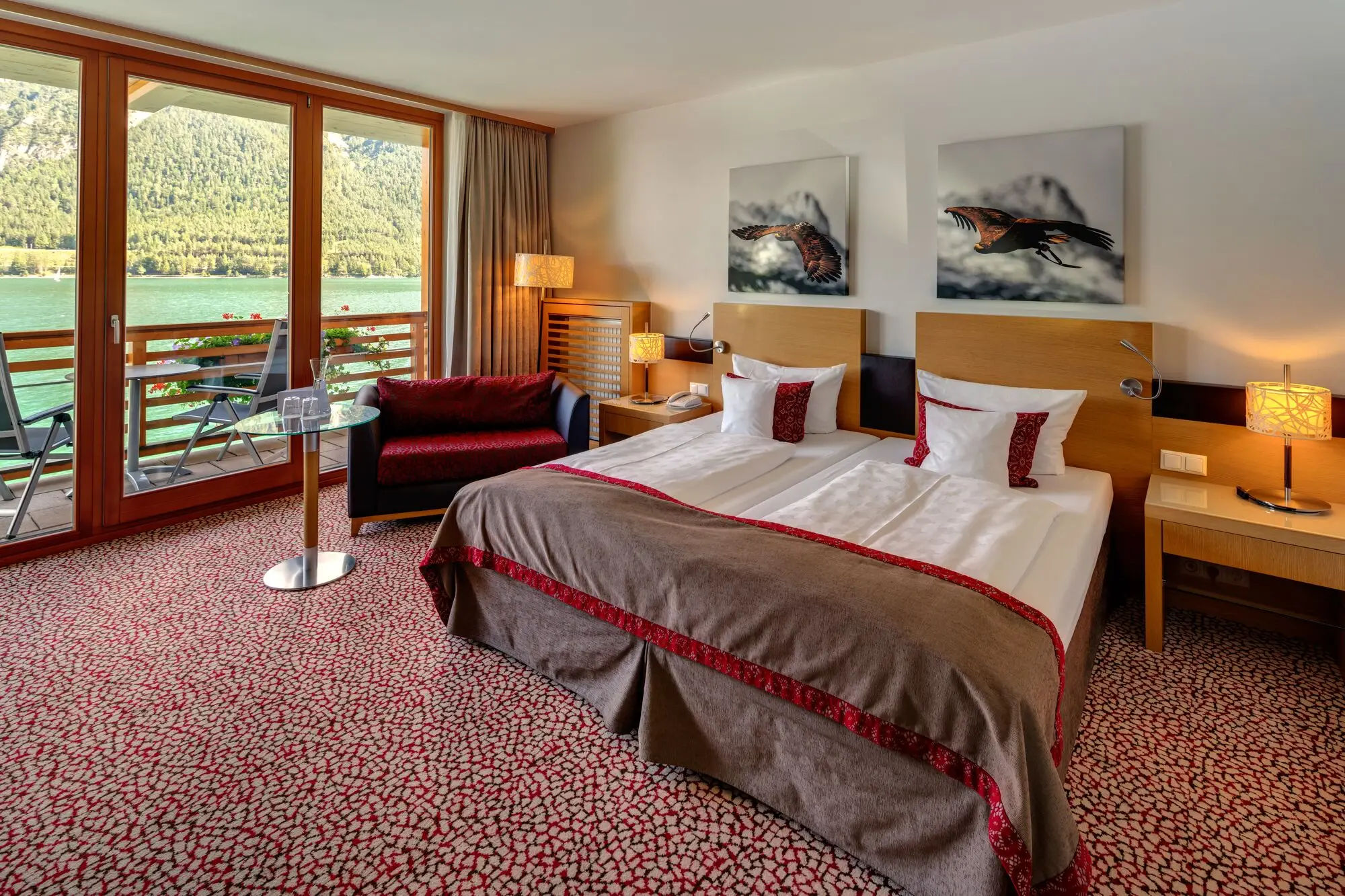 Innenansicht eines Schlafzimmers mit einem Bett, einem Stuhl, einem Tisch und dem See im Hintergrund. .