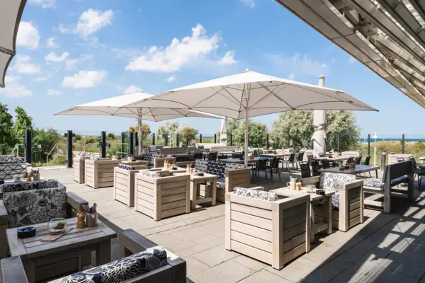 Terrasse im aja Warnemünde Eine Terrasse mit Tischen und Stühlen.