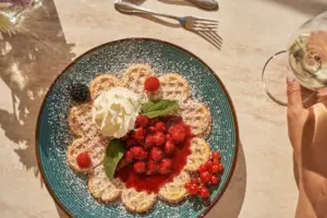 Ein Teller mit einer Waffel mit Beeren und Schlagsahne.
