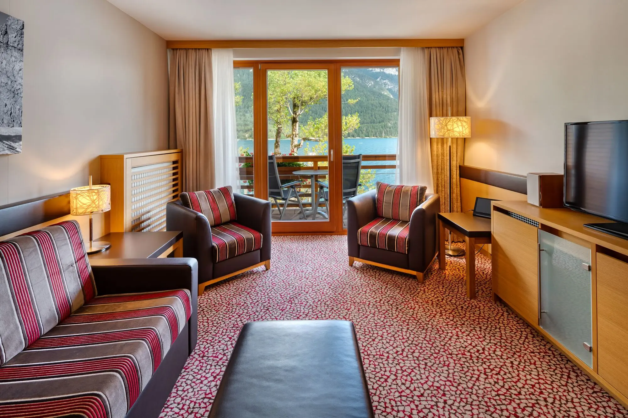 Suite Wohnraum Fürstenhaus am Achensee Wohnbereich eines Hotelzimmers mit Couch, Sesseln, Tisch und Fernseher.