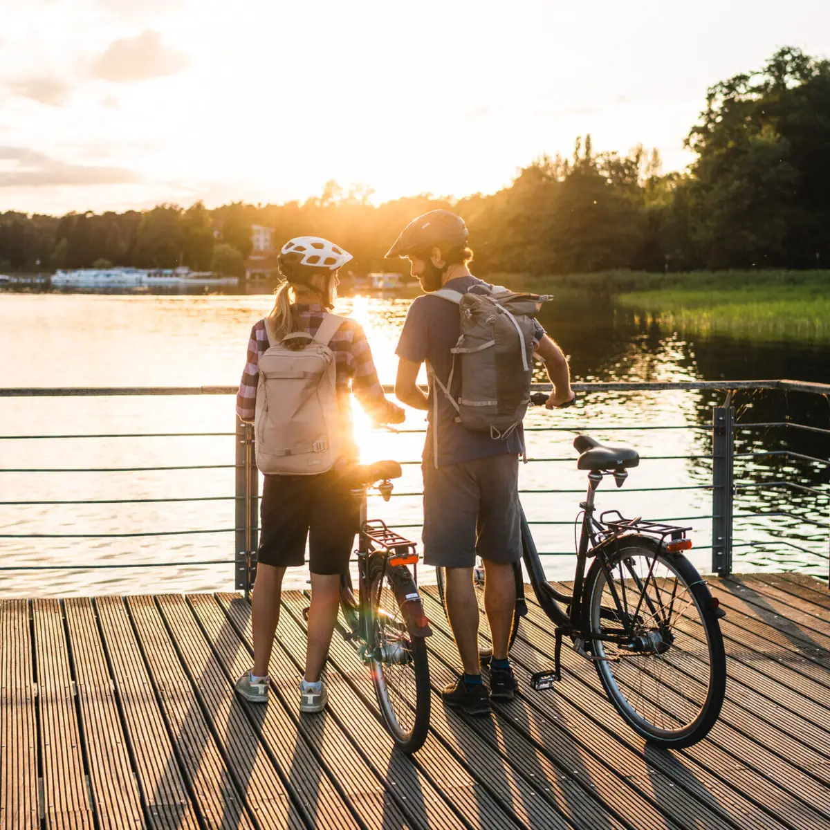 Radfahren am See Ein Mann und eine Frau mit Fahrrädern auf einem Steg.