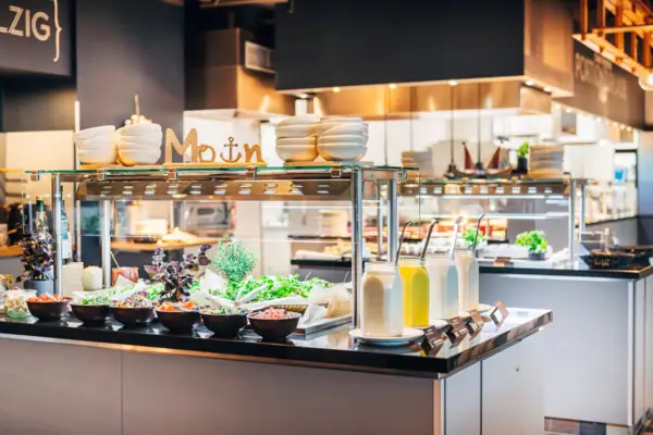 Theke mit Salaten und Gläsern gefüllt mit verschiedenen Dressings.