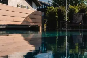 Außenpool Pool mit Stühlen und Sonnenschirmen vor einem Berg.