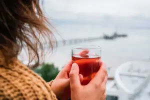 Ausblick Eine Person hält ein Glas mit einem Getränk.