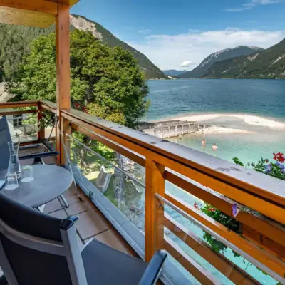 Balkon mit Blick auf den See Ein Balkon mit Tisch und Stühlen mit Blick auf ein Gewässer.