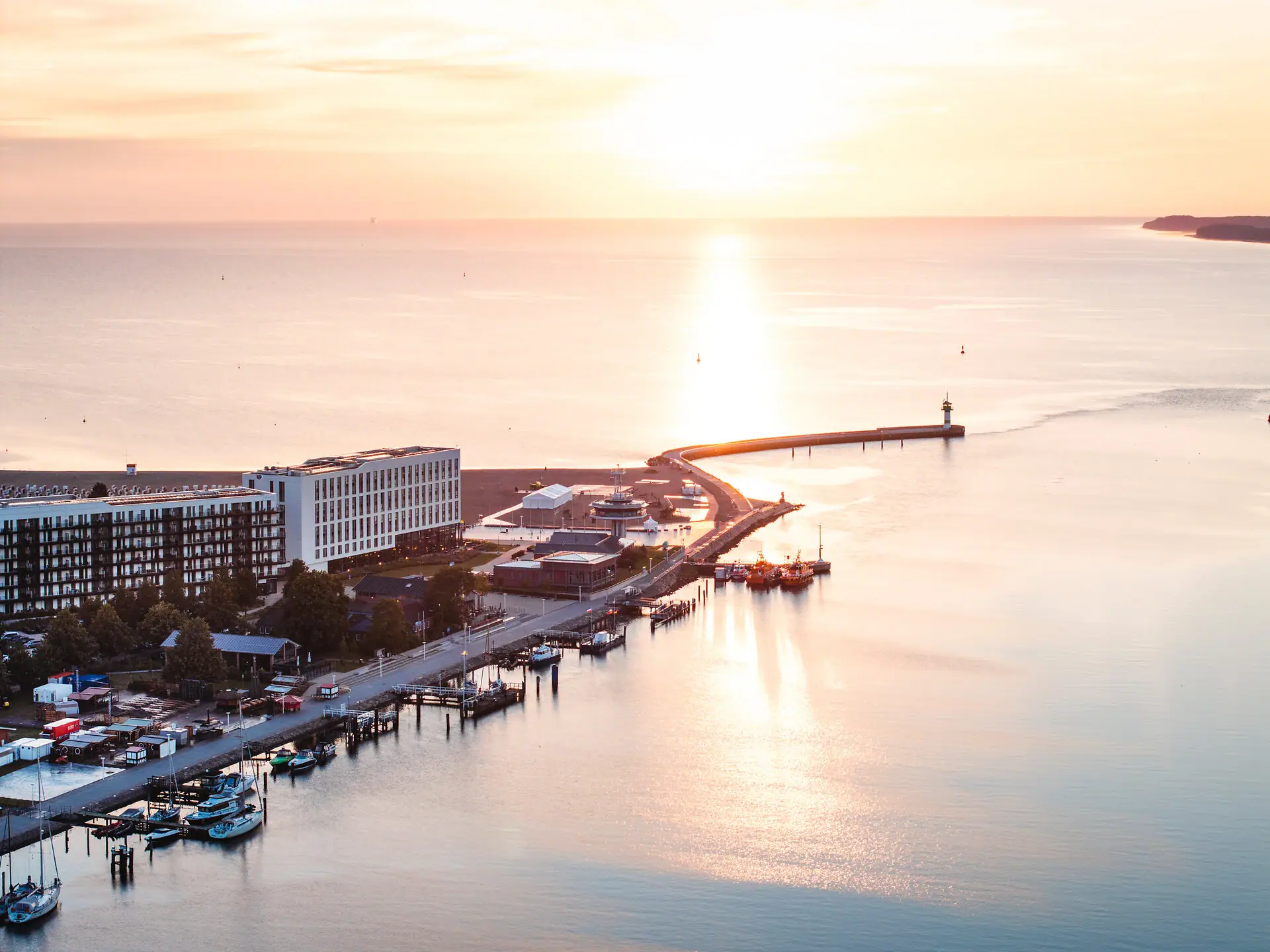 aja Travemünde Das aja Travemünde direkt am Wasser gelegen mit einem Leuchtturm im Hintergrund.