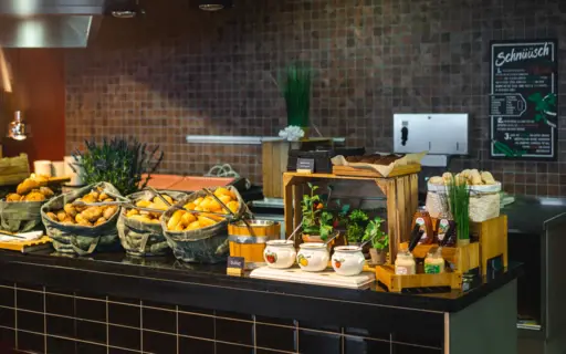Eine grau geflieste Buffetstation mit Brötchenkörben und verschiedenen Marmeladen. Eine grau geflieste Buffetstation mit Brötchenkörben und verschiedenen Marmeladen.