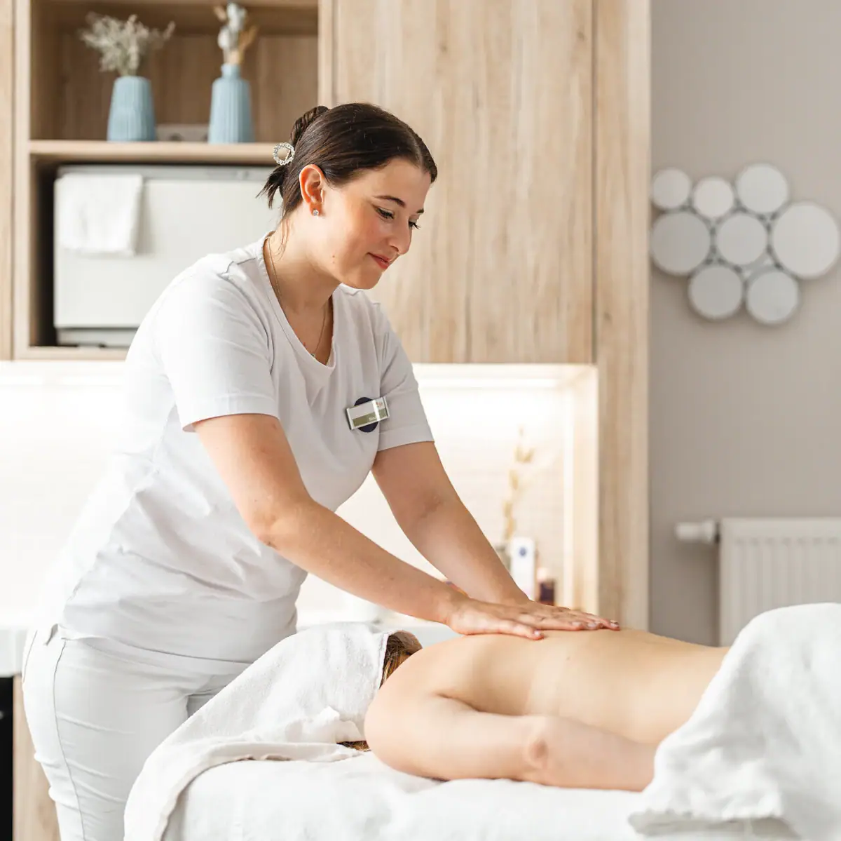 Massage Eine Frau massiert den Rücken einer anderen Frau.