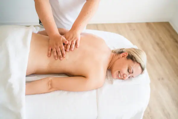 aja Anwendung Eine Frau liegt auf einem Massagetisch.