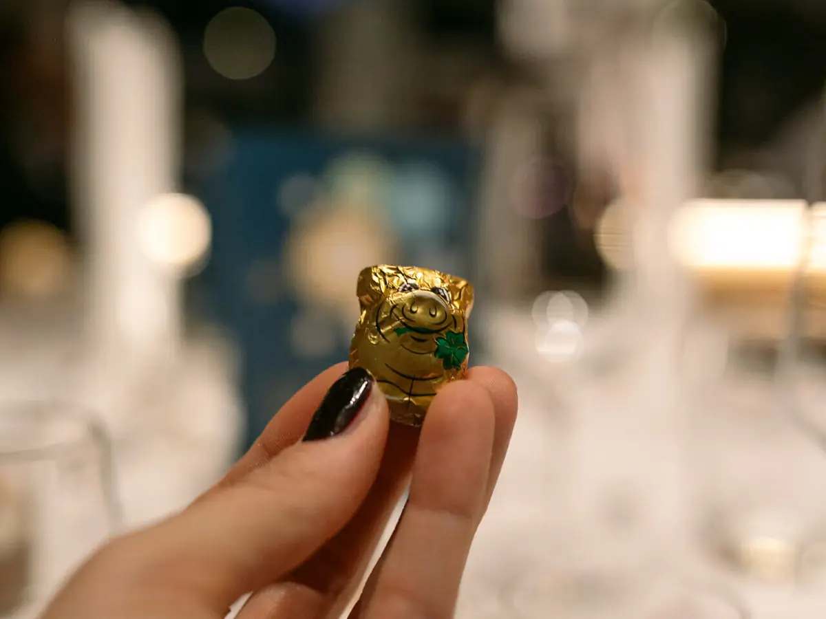 Silvester im aja Ruhpolding Eine Hand hält ein kleines eingewickeltes Glücksschwein aus Schokolade.