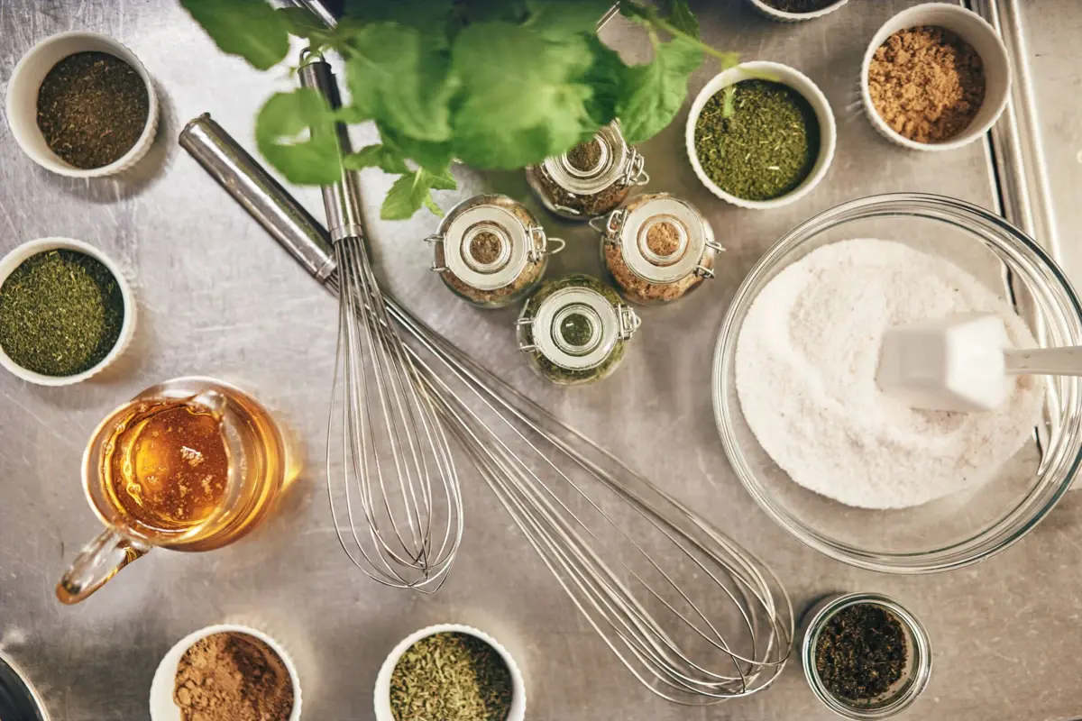 Naturprodukte Eine Gruppe von Gewürzen und eine Schüssel mit Mehl und Schneebesen.