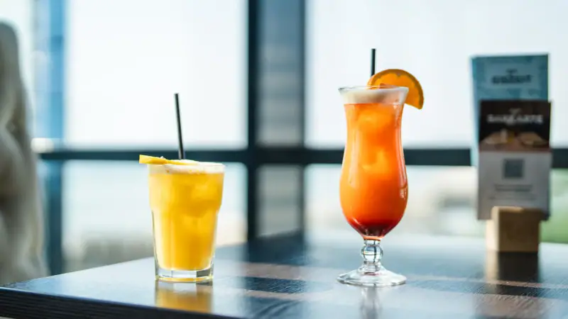 Cocktails Zwei Gläser mit Getränken auf einem Tisch, eines mit Orangensaft und das andere mit Cocktailgarnitur.